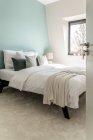 Interior do quarto contemporâneo com cama com travesseiros macios colocados perto da janela no apartamento em estilo mínimo — Fotografia de Stock
