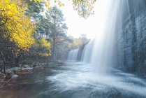 Veduta panoramica della cascata che scorre lungo le rocce nei boschi di montagna in autunno in una lunga esposizione al fiume Lozoya nel Parco Nazionale di Guadarrama — Foto stock