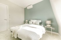 Intérieur de la chambre contemporaine avec lit avec oreillers doux placés près de la fenêtre dans l'appartement dans un style minimal — Photo de stock