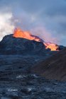 Picturesque view of Fagradalsfjall with fast fire and lava under diffusing smoke in mountains with fluffy clouds in Iceland — Stock Photo