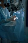 Обрізати анонімного очного хірурга з ручними інструментами, що працюють пацієнт на медичному ліжку в лікарні на розмитому фоні — стокове фото