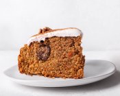 Peça de bolo de cenoura saborosa com noz e canela em pó na cobertura de açúcar de confeiteiro em fundo leve — Fotografia de Stock
