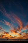 Cielo del atardecer con vívidas nubes anaranjadas situadas sobre el agua de mar con barcos por la noche en Fuerteventura, España - foto de stock