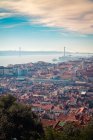 Drone vista di edifici con tetto rosso situato sulla costa del fiume Tago non lontano dal ponte 25 de Abril al mattino a Lisbona, Portogallo — Foto stock