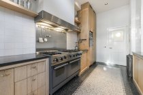 Современный интерьер просторной кухни с деревянными шкафами и новой техникой в квартире — стоковое фото