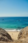 Strand mit Segelbooten im Hintergrund auf türkisfarbenem Meer unter wolkenverhangenem Himmel an einem sonnigen Sommertag auf Fuerteventura, Spanien — Stockfoto