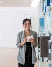 Femmina in bicchieri utilizzando tablet mentre in piedi in un luogo di lavoro spazioso e lavorare sul progetto — Foto stock