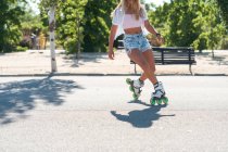 Cropped unrecognizable fit female in rollerblades showing stunt on road in city in summer — Stock Photo