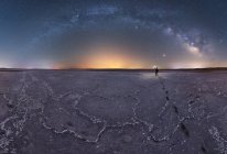 Silhouette de l'explorateur debout dans un lagon de sel sec tenant une lampe de poche sur fond de ciel étoilé avec la Voie lactée lumineuse la nuit — Photo de stock