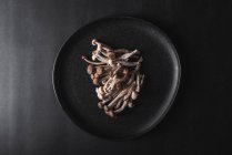 Vista dall'alto di funghi shimeji freschi serviti su piatto nero su tavolo scuro in studio — Foto stock