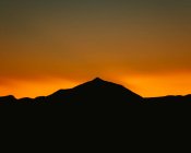 Breathtaking landscape of silhouette of mountain range on background of bright orange sundown sky — Stock Photo