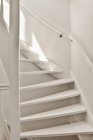Фрагмент дизайну інтер'єру сучасної квартири з білими стінами і сходами з перилами на сонячному світлі — стокове фото