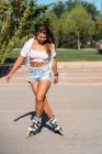Молодая женщина в роликах показывает трюк на дороге в городе летом — стоковое фото