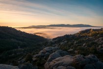 Vue panoramique de Pedriza avec brume diffusant entre la chaîne de montagnes de Guadarrama et des rochers avec des conifères au lever du soleil en Espagne — Photo de stock