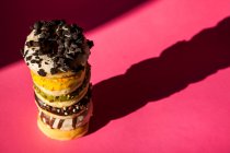 Von oben Turm von Donuts in verschiedenen Farben und Geschmacksrichtungen auf rosa Hintergrund — Stockfoto