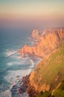Vista de cima da água do mar salpicando perto de rochas do Cabo Roca localizado no Parque Natural de Sintra Cascais ao nascer do sol em Portugal — Fotografia de Stock