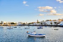 Viele Boote treiben auf dem plätschernden Flusswasser in der Nähe der Stadt vor wolkenlosem blauem Himmel auf Fuerteventura, Spanien — Stockfoto