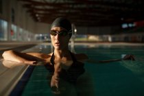 Jovem mulher bonita no passeio da piscina interior, com maiô preto — Fotografia de Stock