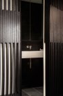 Durch Tür aus weißem Waschbecken im modernen Badezimmer mit schwarz gefliesten Wänden und Fußboden — Stockfoto