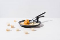 Pezzi di pane serviti su tavolo bianco con appetitoso uovo fritto su padella con forchetta — Foto stock