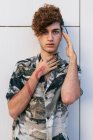 Junger eitler Mann in stylischer Kleidung mit langen Nägeln steht an einer gefliesten Wand und blickt in die Kamera — Stockfoto