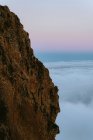 Захватывающие пейзажи скалистой местности в высокогорье, окруженной густыми облаками на закате — стоковое фото