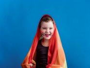Fille souriante avec joue peinte avec drapeau multicolore sur fond bleu vif — Photo de stock