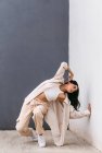 Creative female dancer dancing in city street and leaning on wall during performance — Stock Photo