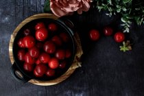 Vue du dessus du bol avec des prunes fraîches sucrées servies sur une table noire — Photo de stock