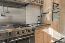 Moderne Einrichtung der geräumigen Küche mit Holzschränken und neuen Geräten in der Wohnung — Stockfoto
