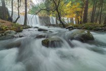 Vista panoramica del monte con cascate e fiume con fluidi di acqua schiumosa su pietre tra alberi autunnali a Lozoya, Madrid, Spagna. — Foto stock