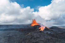 Malerischer Blick auf den Fagradalsfjall mit schnellem Feuer und Lava unter diffusem Rauch in Bergen mit flauschigen Wolken in Island — Stockfoto