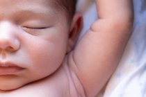 Top view of cute small adorable naked newborn baby sleeping lying on soft bed at home — Stock Photo