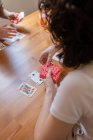 Dall'alto anonimo felice coppia LGBT di donne sedute a tavola e giocare a carte mentre intrattenere nel fine settimana a casa — Foto stock