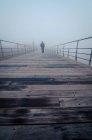 Pessoa irreconhecível passeando em cais de madeira em névoa espessa de manhã em Lisboa, Portugal — Fotografia de Stock