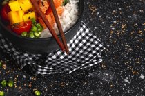 Високий кут азіатського поту з лососем і рисом з асортированими овочами подається в мисці на столі з паличками в ресторані. — стокове фото