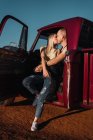 Young couple in love sitting in red vintage pickup and kissing in sunset in summer — Stock Photo