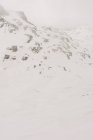 Анонимные спортсмены на лыжах на Пико Аунаменди в заснеженных Пиренеях под облачным небом в Наварре, Испания — стоковое фото