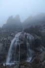 Espectacular vista de cascadas con puros fluidos acuáticos en el monte bajo el cielo brumoso en otoño - foto de stock