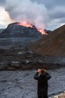 На зворотному боці нерозпізнаного мандрівника, який фотографується на Fagradalsfjall з вогнем і лавою стоячи на горі в Ісландії. — стокове фото