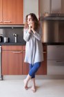 Frau mit lockigem Haar sitzt in der Küche und nimmt eine Infusion — Stockfoto