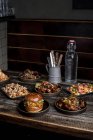 Подається дерев'яний стіл з апетитними бургерами та курячими крильцями в ресторані вуличної їжі — стокове фото