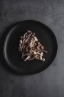 Vista superior de champiñones shimeji frescos servidos en plato negro sobre mesa oscura en estudio - foto de stock