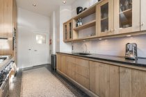 Сучасний інтер'єр просторої кухні з дерев'яними шафами і новою побутовою технікою в квартирі — стокове фото
