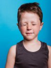 Content adorable preteen boy with closed eyes on bright blue background in studio — Stock Photo