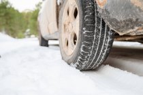 Nivel del suelo del neumático de la rueda del automóvil estacionado en la carretera nevada en el bosque de invierno - foto de stock