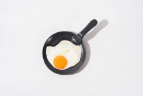 Delizioso uovo fritto su padella nera servito sul tavolo su sfondo bianco in studio — Foto stock