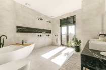 Interior moderno do banheiro com banheira branca e banheiro montado na parede de cerâmica e pias duplas em estilo mínimo — Fotografia de Stock
