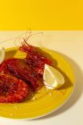Tasty seafood of cooked red shrimps with fresh lemon slices and coarse salt on two color background — Stock Photo