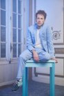 Thoughtful stylish male in suit sitting table in posh room and looking away — Stock Photo